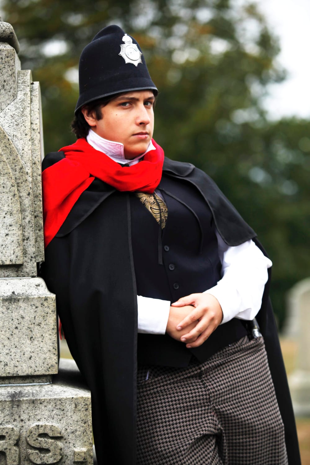 A caped figure in Victorian dress at a London graveside