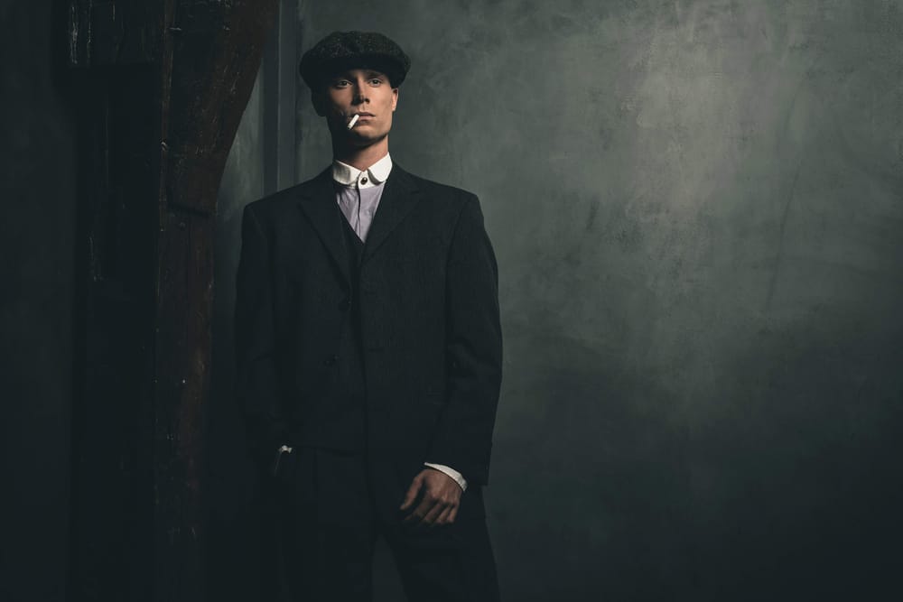 A 1920s gangster in a flat cap, lighting a cigarette